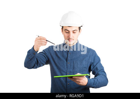 Creative young man engineer wearing protective helmet using a tablet computer and holding a pencil trying to draw a imaginary 3d project plan sketch i Stock Photo