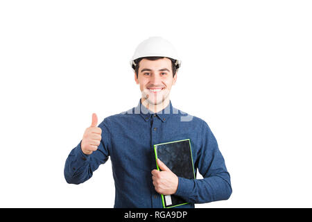 Cheerful young man engineer wearing protective helmet holding tablet computer showing thumb up positive feedback gesture looking to camera and smiling Stock Photo