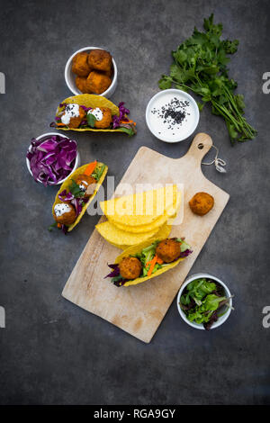 Sweet potato falafel in taco shells, with red cabbage, salad, carrot, yogurt sauce and black sesame Stock Photo
