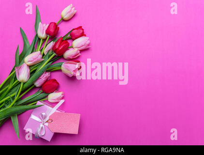 Mothers, womens day concept. Tulips bouquet and gift box with blank tag on bright pink background, top view, copy space Stock Photo