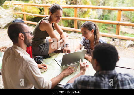 Group of hikers sitting together planning a hiking route using map and laptop Stock Photo