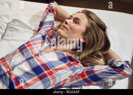 Smiling woman lying on bed relaxing Stock Photo