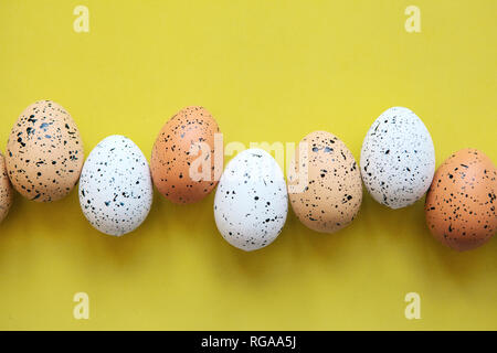 A set of colored eggs on a yellow background in a row. Festive Easter concept. Stock Photo