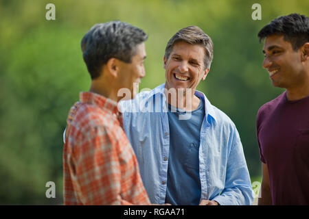 Three friends talking and laughing together. Stock Photo