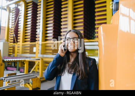 Young woman working in distribution warehouse, talking on the phone Stock Photo
