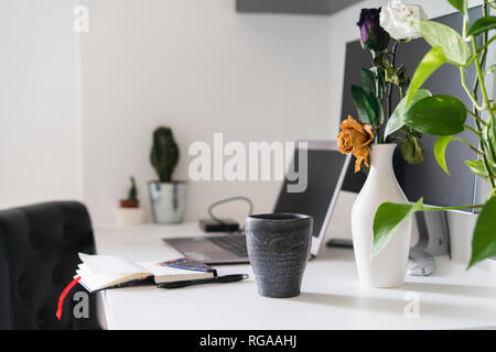 Nptebook, flower and laptop on desk at home Stock Photo