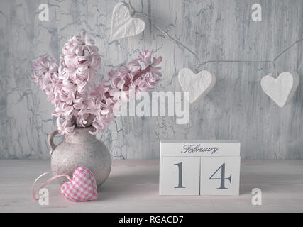 Valentines day still life with wooden calendar, pink hyacinth flowers and garland lights in shape of paper hearts on rustic background Stock Photo