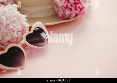 Summer vacation concept. Stylish girly pink retro sunglasses, white and pink peonies, straw hat on pastel pink paper with copy space. Hello spring con Stock Photo