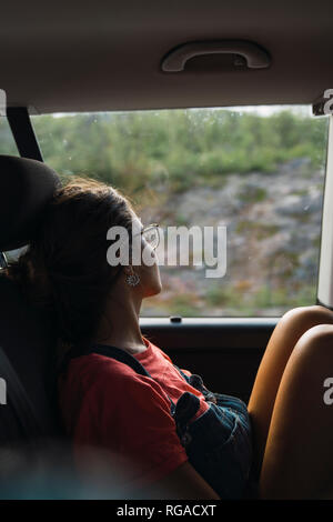 Young woman sitting on back seat of a van, looking out of window, traveling through Norway Stock Photo