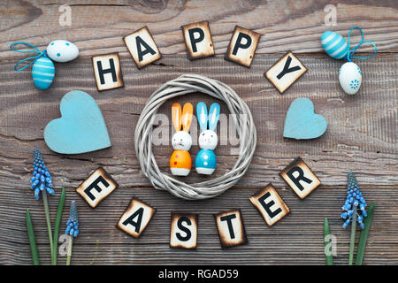 Happy Easter lettering text on rustic wood with blue hyacinth flowers, Easter eggs, wooden heart and decorations Stock Photo
