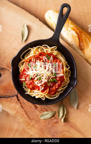 Food concept Homemade spaghetti bolognese in iron cast on wooden blackground Stock Photo