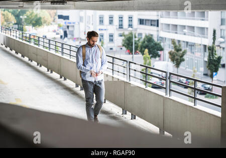 Young businessman walking in parking garage, using smartphone Stock Photo