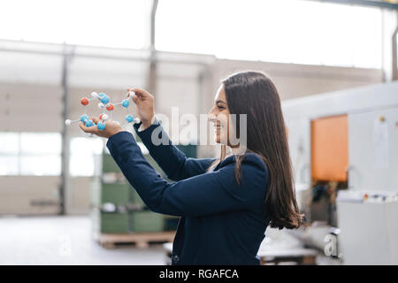 Confident woman working in high tech enterprise, holding molecule model Stock Photo