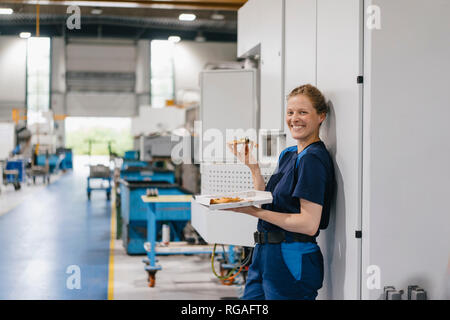 Woman working in high tech company, taking a break, eating pizza Stock Photo