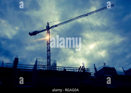 silhouettes of a construction crane and building in progress at a construction site Stock Photo