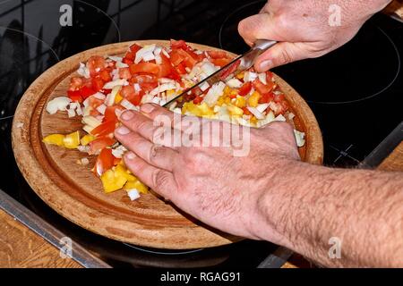 Chef slicing Onion, Allium cepa on the cutting board with a knife. Stock Photo