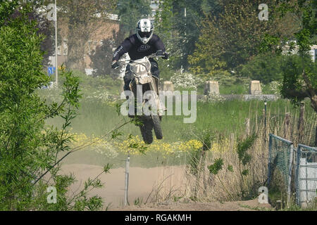 A motorcyclist is jumping in the air during a race. Photographed at an amateur motorcycle race in Gouda, The Netherlands. May 11th 2017. Stock Photo