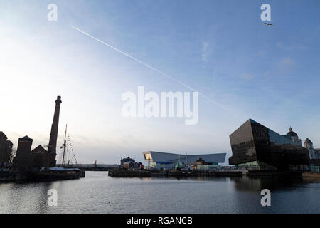 A vapour trail in the sky above the Museum of Liverpool and RIBA North in Liverpool, England. The buildings are seen across the water of the Canning D Stock Photo