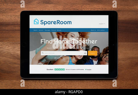 The website of SpareRoom is seen on an iPad tablet, which is resting on a wooden table (Editorial use only). Stock Photo