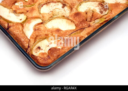 Cooked tasty pie with apples and cinnamon in transparent glass bowl on green tablecloth on the table side view closeup Stock Photo