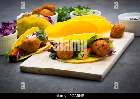 Sweet potato falafel in taco shells, with red cabbage, salad, carrot, yogurt sauce and black sesame Stock Photo
