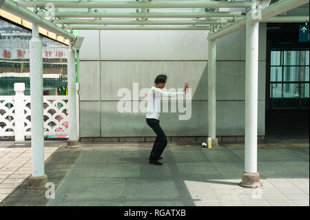 18.04.2018, Singapore, Republic of Singapore, Asia - A man practices Tai chi at a small park outside the People's Park Complex in Chinatown. Stock Photo