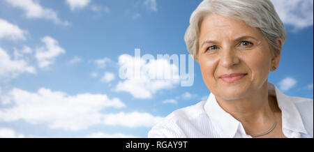 portrait of smiling senior woman over blue sky Stock Photo