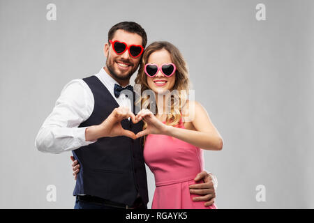 couple in sunglasses making hand heart gesture Stock Photo
