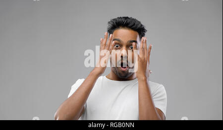 shocked indian man over grey background Stock Photo