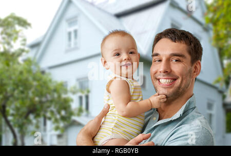 happy father holding baby daughter over house Stock Photo
