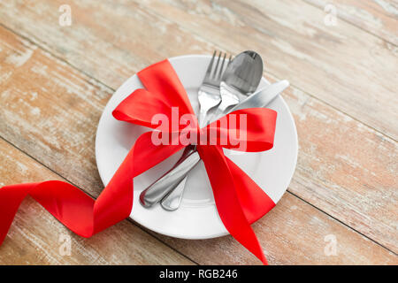 cutlery tied with red ribbon on set of plates Stock Photo