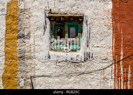 White painted facade of a traditional house inside the walled town with a colorful window and flowers Stock Photo