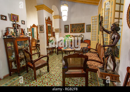 Room of a colonial house, armchairs, armchairs and old sofa and large paintings decorating a wall Stock Photo