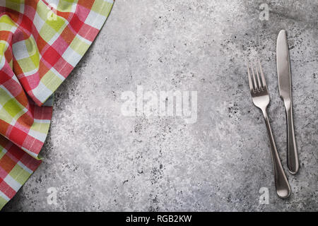 Fork, knife and checkered tablecloth on a table with a concrete texture, top view. Food background Stock Photo