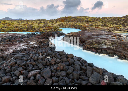 Dramatic landscape of a beautiful volcanic terrain with black volcanic rocks and turquoise water at Blue Lagoon near Grindavik in Reykjanes peninsula  Stock Photo