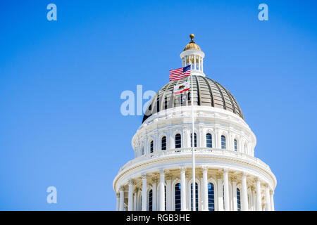 April 14, 2018 Sacramento / CA / USA - The US and the California state flag waving in the wind in front of the dome of the California State Capitol Stock Photo