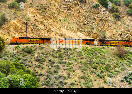 May 25, 2018 Tehachapi / CA / USA - Distinctive orange and yellow Burlington Northern Santa Fe (BNSF) engines travelling through the mountains Stock Photo