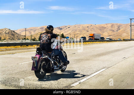 June 10, 2018 Los Angeles / CA / USA - Biker riding a Harley Davidson motorcycle on the interstate; golden hills and blue sky in the background Stock Photo