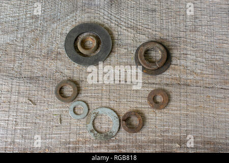 A happy face arranged from rusty metal washers placed on a rough piece of light grey timber. Stock Photo