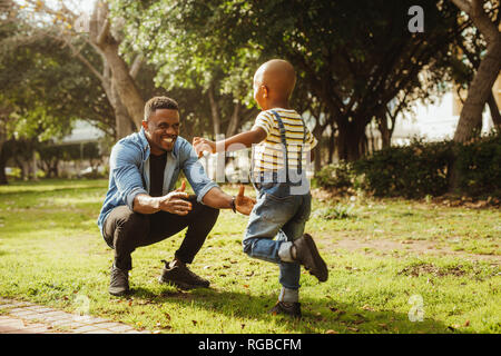 Cute son running into father's arms. Boy rushing into father's embrace at the park. Stock Photo