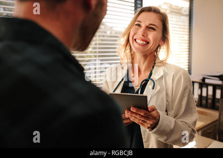 Female doctor consulting a patient in clinic. Smiling female medical professional interacting with a patient. Stock Photo