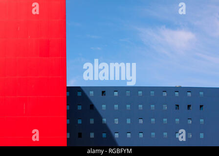 Buildings in modern contemporary architecture with minimalistic geometric patterns in red and blue colors against a blue sky with copy space Stock Photo