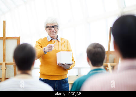 Portrait of senior art teacher talking to group of students during lecture in college, copy space Stock Photo