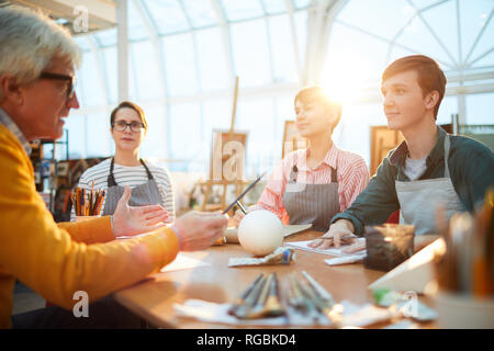 Portrait of group of students listening to senior art teacher during lecture in sunlit art studio Stock Photo