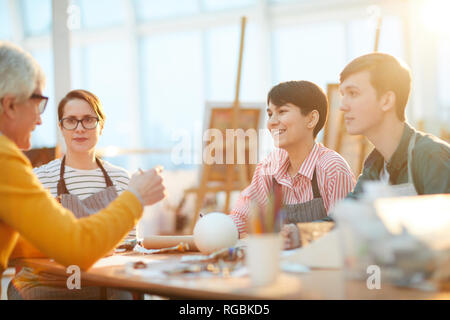 Portrait of group of happy students listening to senior art teacher during lecture in sunlit art studio Stock Photo
