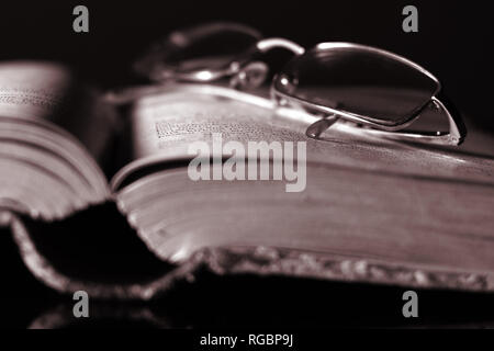 Glasses and old book. Monochrome close up image. Shallow depth of field.