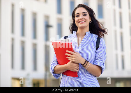 Portrait of smiling student with notebooks on campus Stock Photo