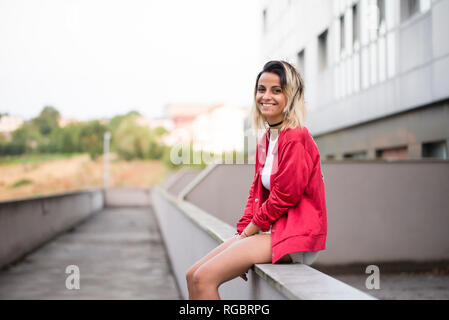 Laughing young woman sitting on a wall Stock Photo