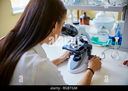 Young woman using microscope in laboratory Stock Photo