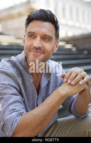 Portrait of smiling mature man sitting  on stairs Stock Photo